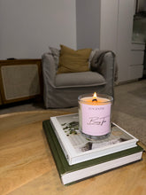 Load image into Gallery viewer, Candle labeled 'Berry Tea' on a stack of books with a cozy living room background