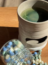 Load image into Gallery viewer, Ceramic container with green liquid on a wooden surface, next to a jar of colorful candies.