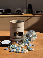 Load image into Gallery viewer, Ceramic diffuser with scattered pellets on a wooden surface
